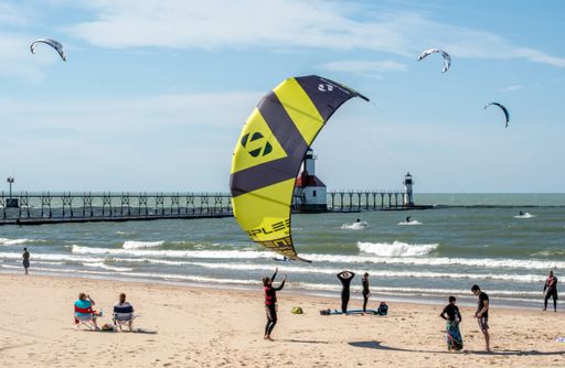 The active people surf and kiteboard on Lake Michigan near the lighthouse in St. Joseph, US