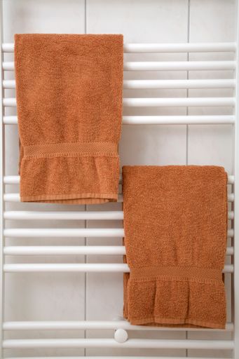 A vertical shot of brown towels hanging on a dryer in a bathroom