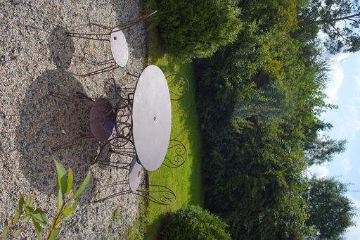 A closeup shot of a French garden in Normandy with ametal table and  gravel floor
