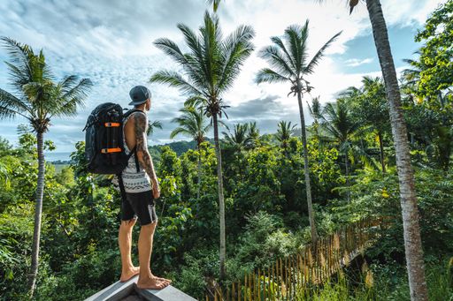 A man with a backpack looking at the jungle in Lombok, Indonesia