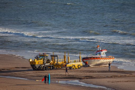 members of the dutch coastguard haul a lifeboat from the north sea onto a caterpillar after a rescue drill