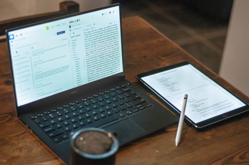 A high angle shot of laptop, tablet, digital pen and a cup of freshly brewed coffee on a wooden table, nice work from home setting