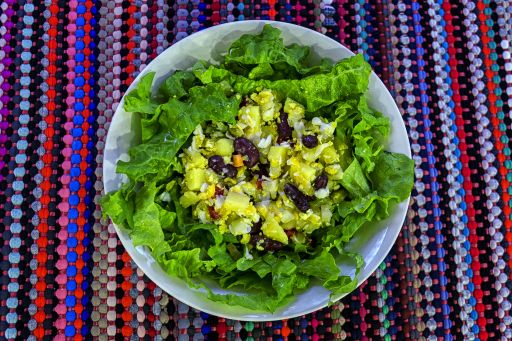 An overhead closeup shot of potato, lettuce, kidney bean, egg, and red bell pepper salad