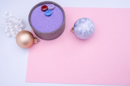 vase with colored sand and Christmas ball decorations on a white background with copy space