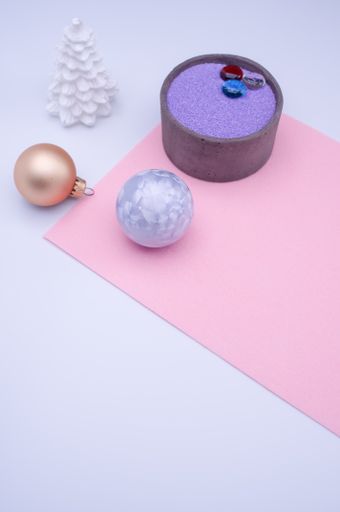 vase with colored sand and Christmas ball decorations on a white background with copy space