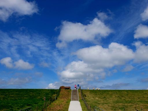 A beautiful view of a blue partly cloudy sky above dyke