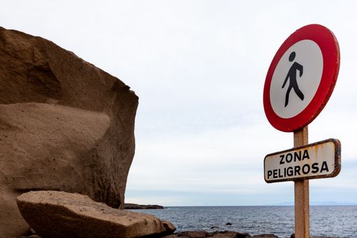 A warning sign saying danger zone near a beach
