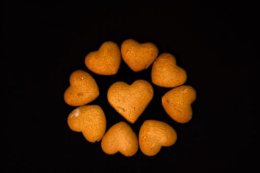 A top view of 9 Heart-Shaped cookies on black background. National Cookie Day on a black background