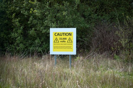 Sign warning of high voltage cables buried in ground.