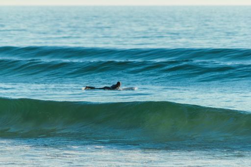 A surfer lying down on the waves of the beach
