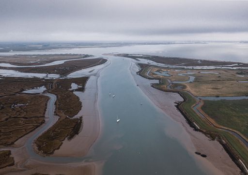 An aerial shot of a wide river slowly flowing through the vast valley