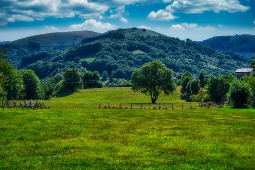 A landscape view of Elizondo with the beautiful mountains and green trees under a blue cloudy sky