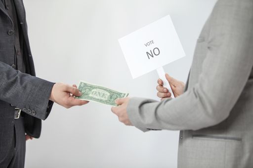 A young man is receiving some money from another person and he is saying no to him.