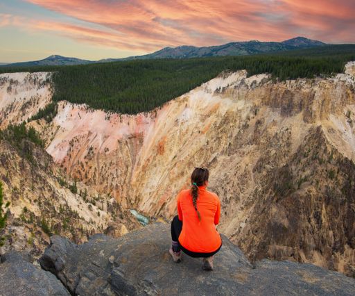 A rear view of a woman hiker resting in Yellowstone National Park, USA during sunset