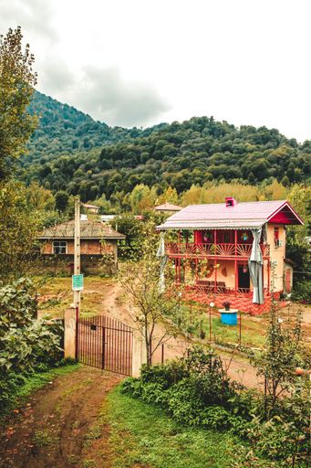A vertical shot of a red rural house on lush vegetation background