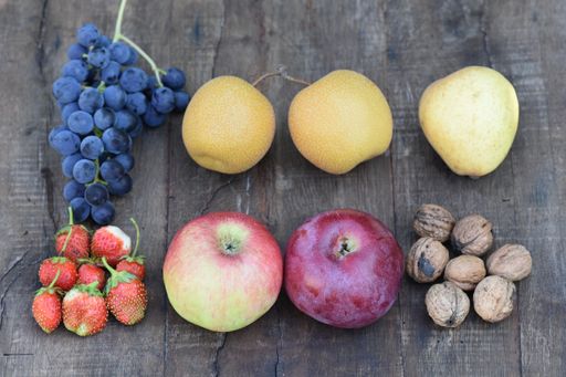 A top view of ripe delicious fruits and nuts isolated on a wooden background