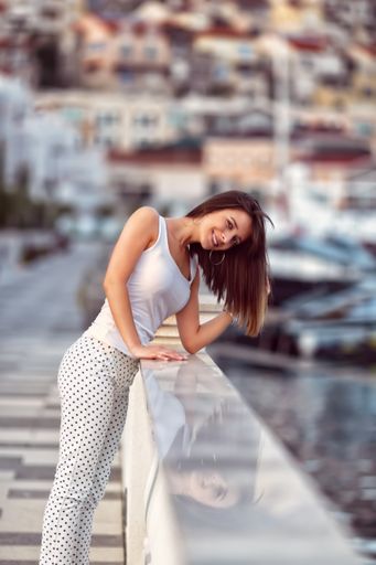 A shallow focus of a caucasian female with a white t-shirt posing on a blurred background of a city