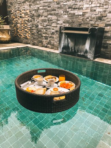 A vertical shot of a straw tray with a breakfast serving in the pool