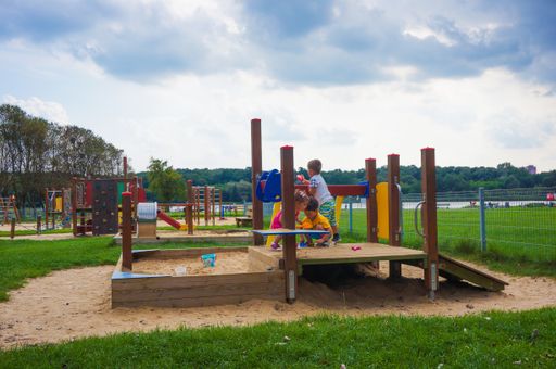 The three children playing on sand equipment on a playground near Rusalka lake on a cloudy day