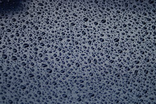 Raindrops form an interesting pattern on a blue plastic chair with reflections after a rain shower.