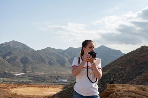A young and pretty girl taking pictures with an analog camera in the abandoned Mazarron mines