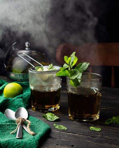 A vertical shot of a couple of beverage glasses decorated with mint leaves and smoke