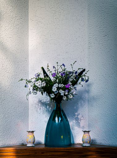 A vertical shot of a blue vase with flowers on the wooden table inside hotel lobby