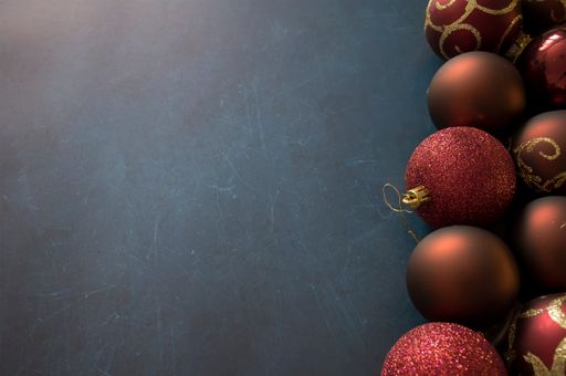 A top view of shiny Christmas ornaments on a dark surface with space for text