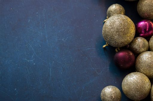 A top view of shiny Christmas ornaments on a dark surface with space for text