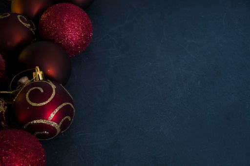 A top view of shiny Christmas ornaments on a dark surface with space for text