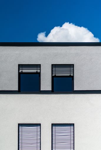 A vertical shot of a modern gray building with windows on a sunny day