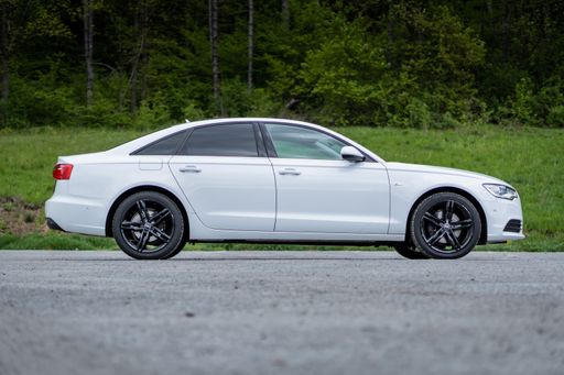 A right-side profile of Audi A6 of the year 2014 S-Line, white metallic paint and black rims