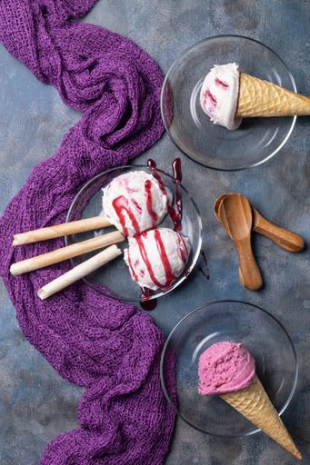 A vertical  top view of a berry ice cream with topping designed with decorations on a gray surface