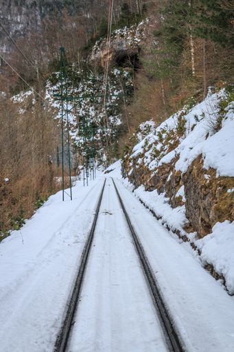A vertical shot of a narrow railroad of a train through the mountains