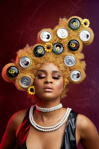 A portrait of a sexy Nigerian woman with blonde afro hair with soda can caps on it