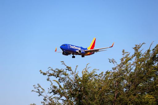 A wide shot of a white, blue, and red Delta Connection airplane in mid-flight against a clear blue sky.