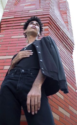 A low angle shot of a Hispanic male in a black outfit posing on the streets in Old Havana, Cuba