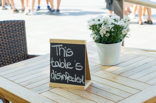Wooden blackboard as table sign on a sanitized table in a restaurant. Preventive measure for the COVID-19 pandemic.