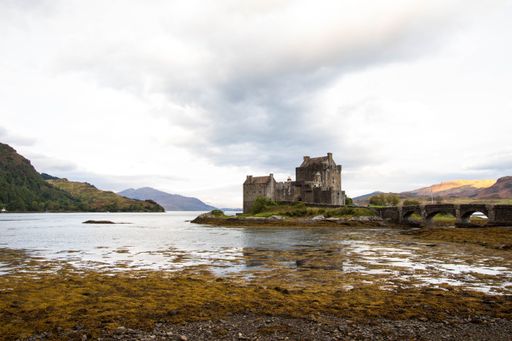 An ancient historic Eilean Donan Castle in the Western Highlands of Scotland under a cloudy sunset sky