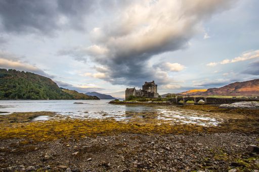 An ancient historic Eilean Donan Castle in the Western Highlands of Scotland under a cloudy sunset sky