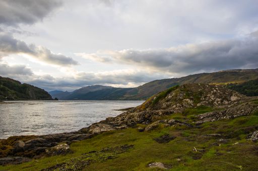 A stunning rocky beach and highlands at Elgol on the Isle of Skye under a cloudy sunset sky, Scotland