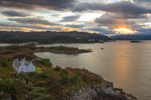 A stunning rocky beach and highlands at Elgol on the Isle of Skye under a cloudy sunset sky, Scotland