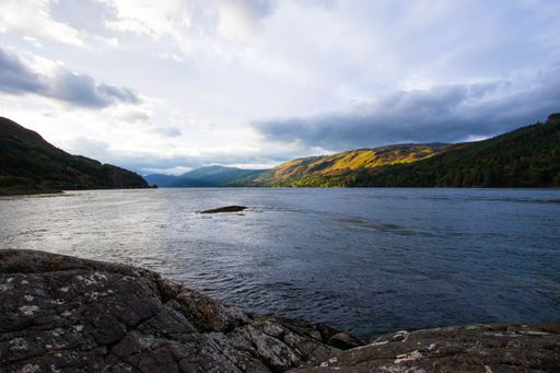 A stunning rocky beach and highlands at Elgol on the Isle of Skye under a cloudy sunset sky, Scotland