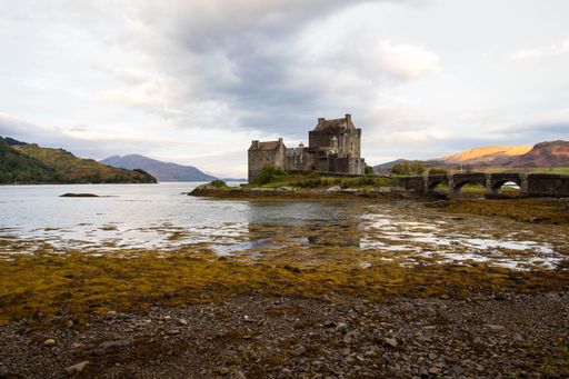 An ancient historic Eilean Donan Castle in the Western Highlands of Scotland under a cloudy sunset sky