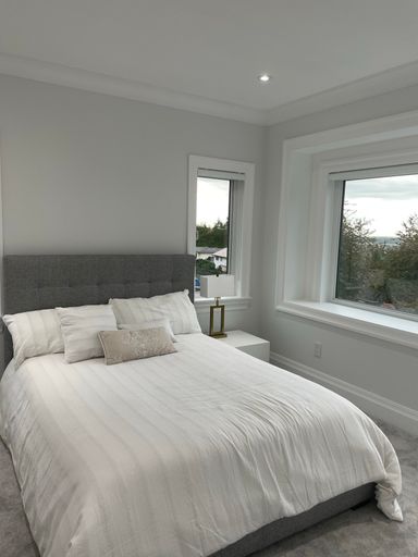 A vertical shot of a nice white bedroom in a newly constructed house in Burnaby, Canada.