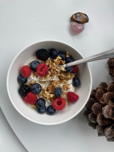 A close up shot of a raspberry, walnut and muesli breakfast bowl on white table