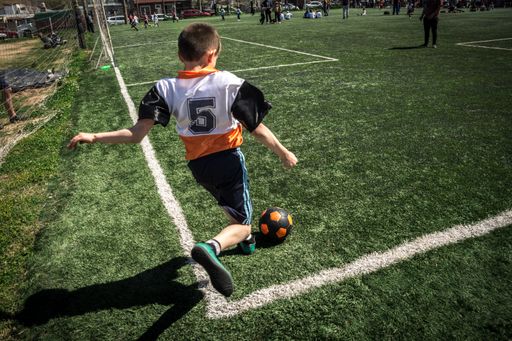 A young soccer player in action on a green field during a sunny day, showcasing youthful energy and passion for the sport.