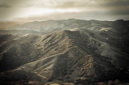 A high angle shot of the beautiful mountain peaks under the dull cloudy sky captured in Italy