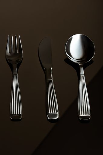 A vertical shot of silver cutlery on a brown background.