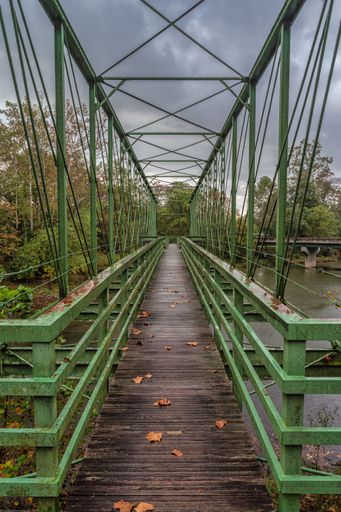 A vertical shot of a bridge with green pillars above the river in West Virginia